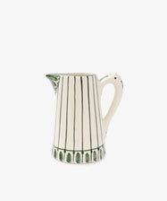 The Jorge Jug is a green-and-white ceramic pitcher with vertical green lines, a flared spout, and a curved handle. Inspired by the classic Portuguese jug and its traditional pattern, it's shown on a plain white background.