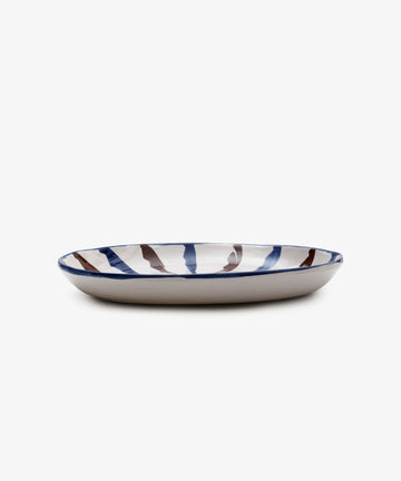 The Rayas Oval Serving Platter is a handmade ceramic plate featuring a white base with blue and brown vertical stripes around the rim, shown on a white background.