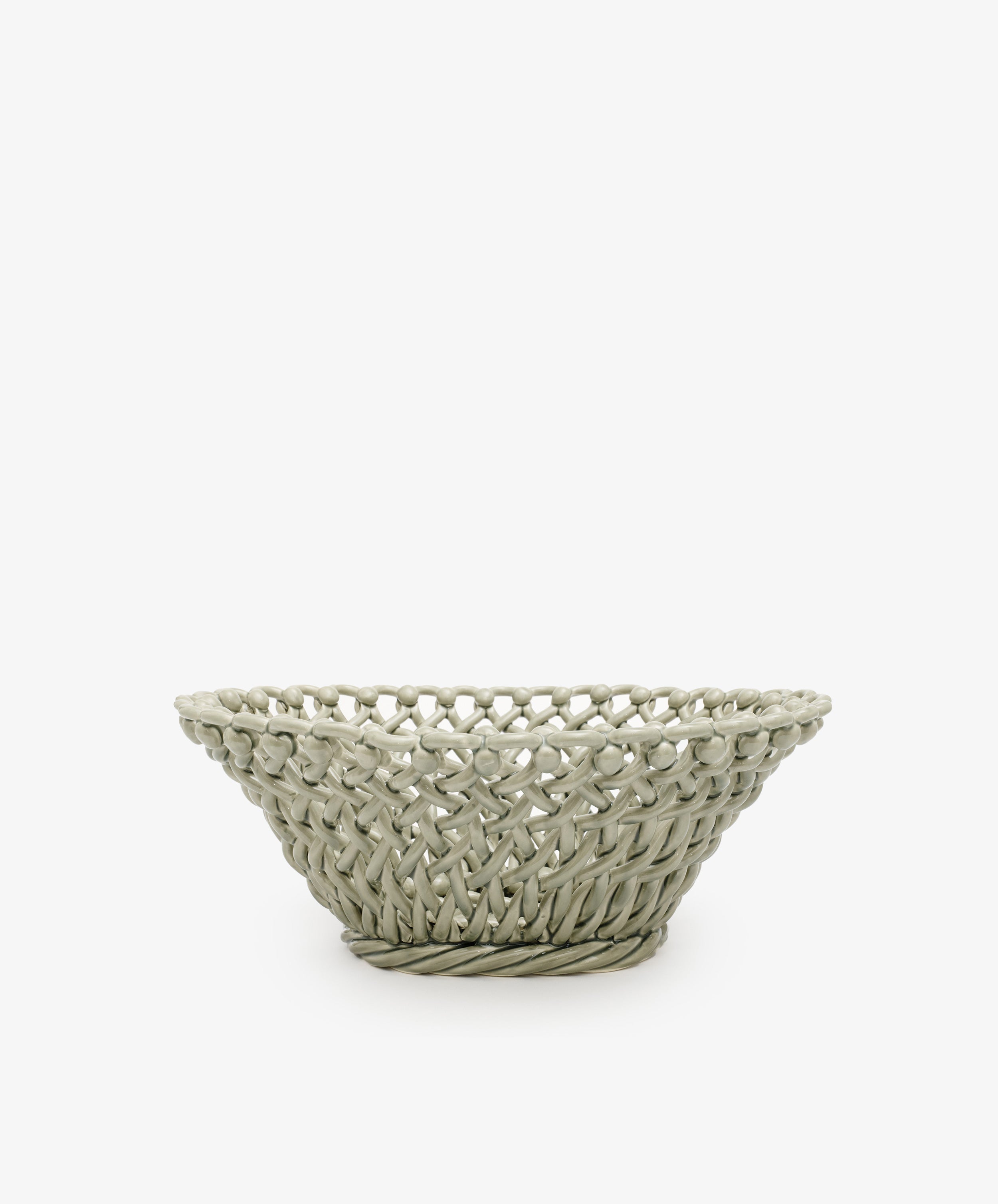 The Remi Decorative Fruit Bowl is a shallow, round, light gray ceramic basket with an open lattice design that makes a striking sculptural statement, shown here as a decorative accent against a plain white background.