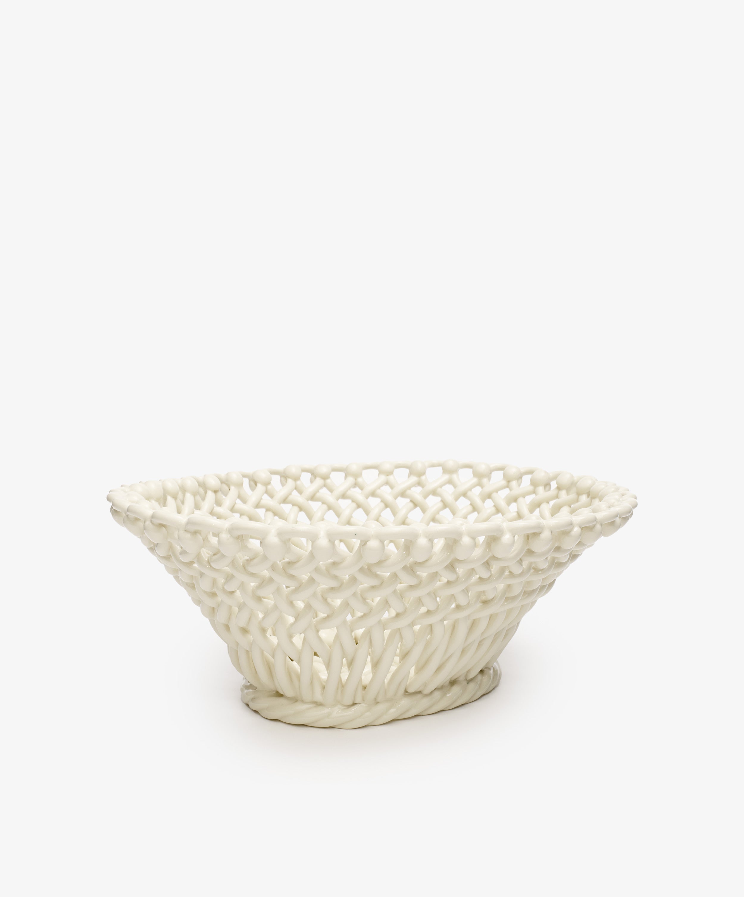 The Remi Decorative Fruit Bowl is a white glazed ceramic basket featuring a hand-braided woven pattern and wide, shallow shape, perfect for displaying fruit. Shown against a plain white background.