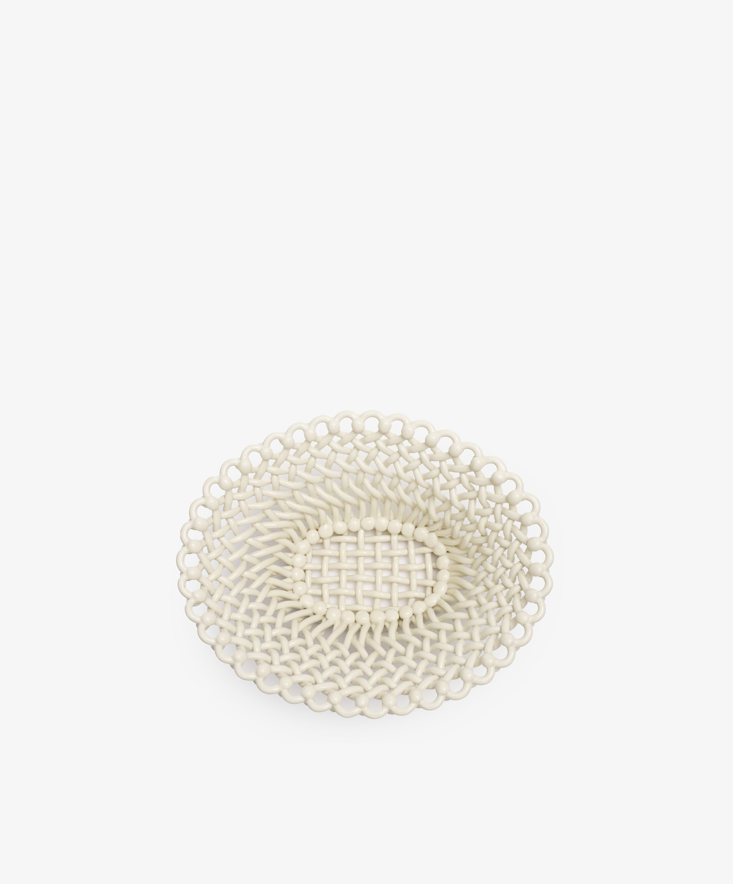 The Remi Decorative Fruit Bowl is a round, off-white woven basket tray featuring a textured pattern and open lattice design, inspired by South of France craftsmanship, shown on a plain white background.