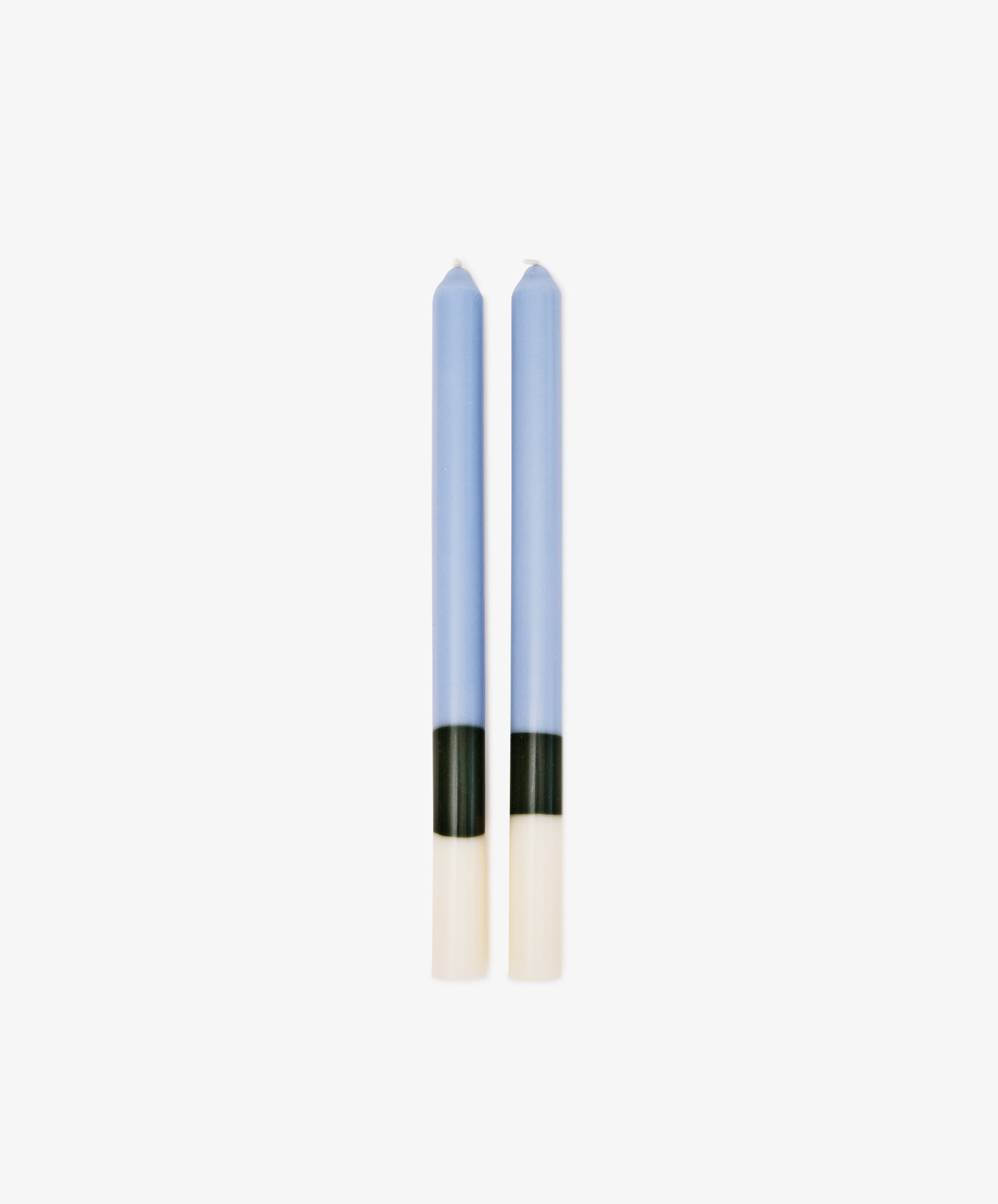 Two Highbury Candles with a blue body and black and white color blocks at the base stand side by side on a white background. These hand-poured sculptural candles bring modern style to any space.