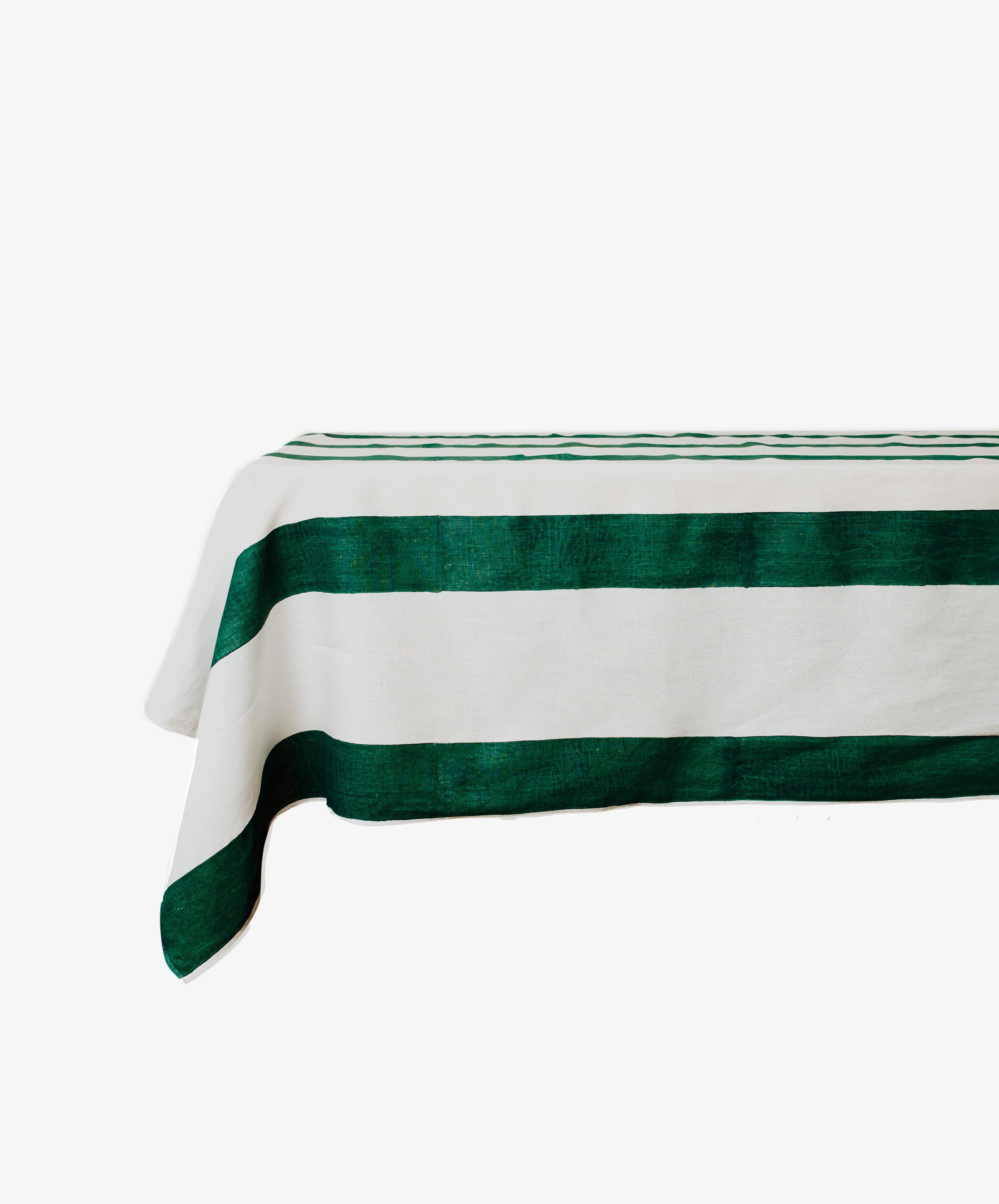The Riga Tablecloth is an artisanal linen tablecloth with bold green horizontal stripes on a crisp white rectangular surface.