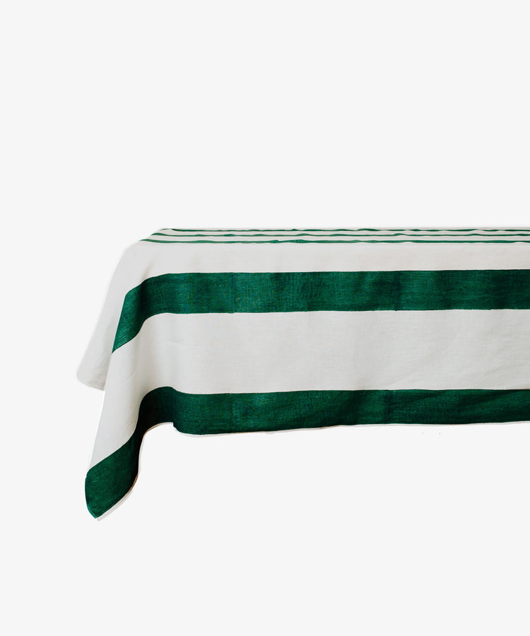 The Riga Tablecloth is an artisanal linen tablecloth with bold green horizontal stripes on a crisp white rectangular surface.