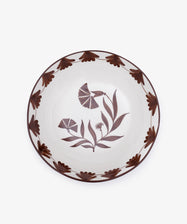 The Catalina Serving Bowl is a round ceramic piece from Portugal, featuring brown floral rim patterns and hand-painted flowers and leaves at the center on a white background.