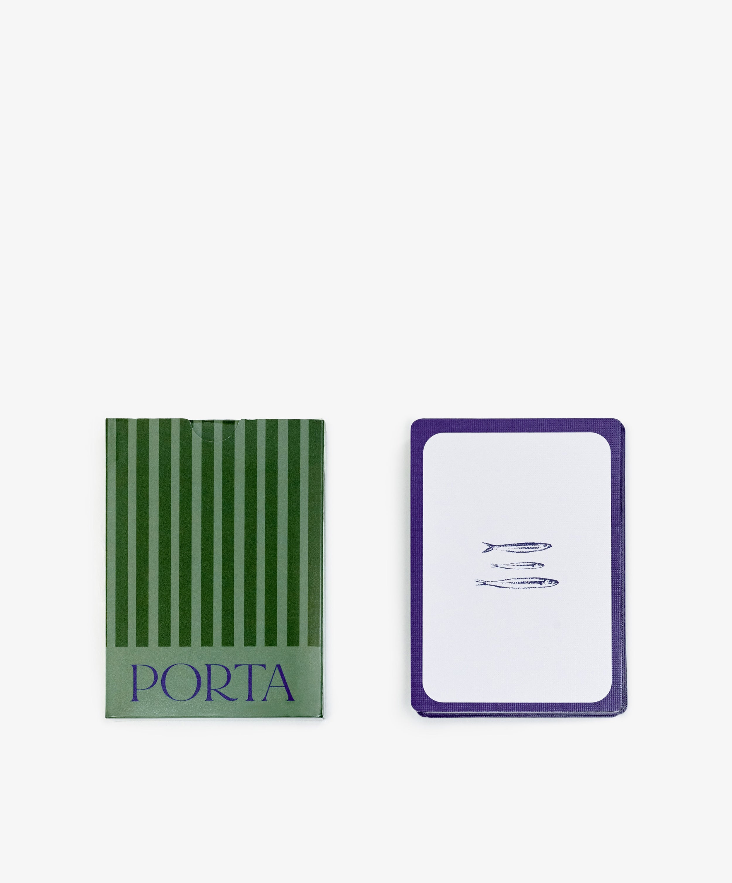 A green striped box labeled PORTA Playing Cards sits beside a playing card with three small fish, highlighting the unique charm of designer playing cards.