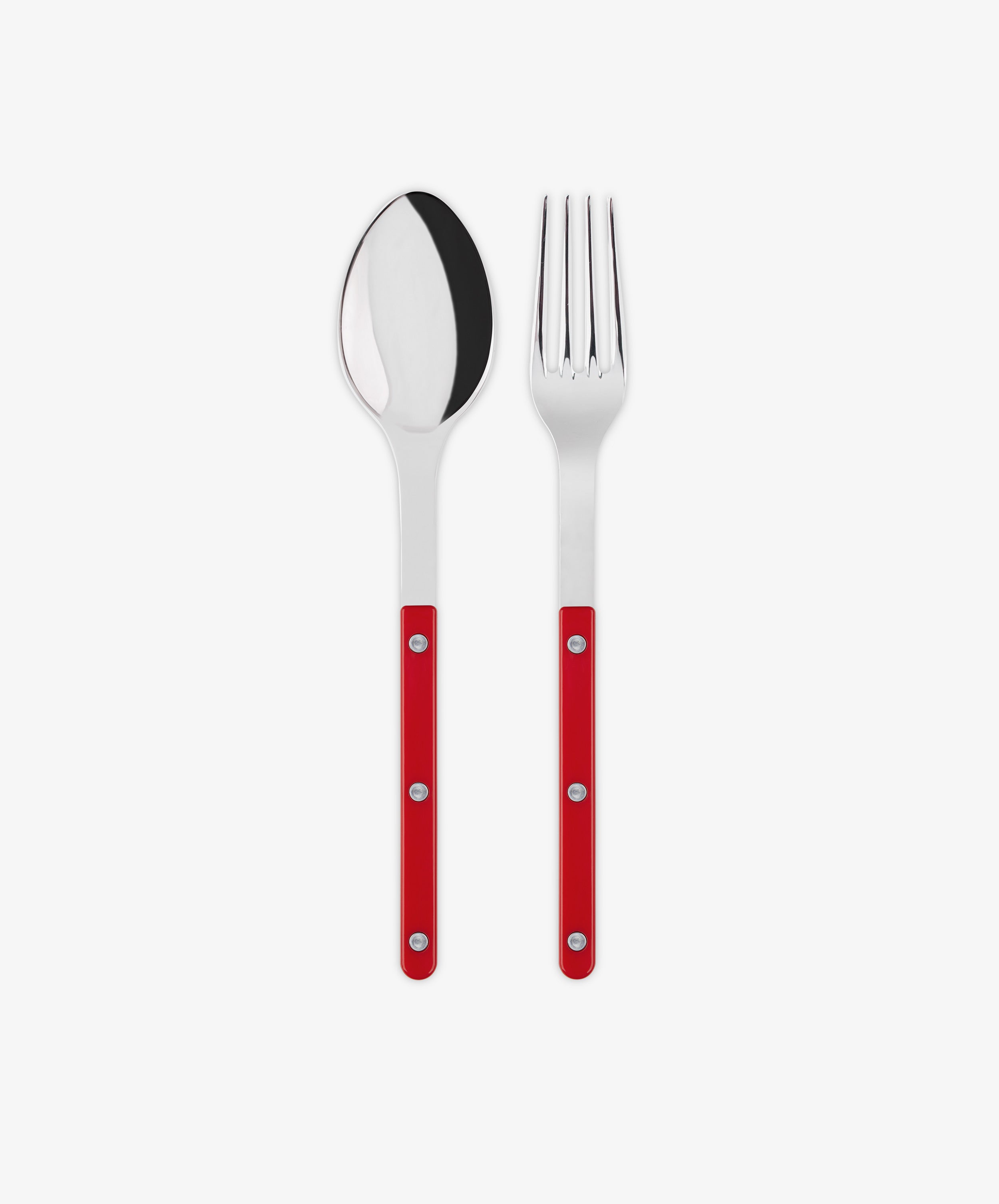 The Bistrot Serving Set, featuring a stainless steel spoon and fork with red handles and silver rivets in Parisian bistro style, is arranged side by side on a white background.