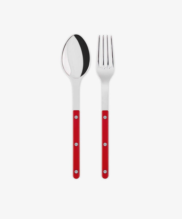 The Bistrot Serving Set, featuring a stainless steel spoon and fork with red handles and silver rivets in Parisian bistro style, is arranged side by side on a white background.