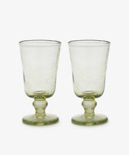 A set of six Elodie Stemmed Wine Glasses with thick stems and a subtle green tint, inspired by handblown Moroccan glassware, is displayed side by side on a white background.