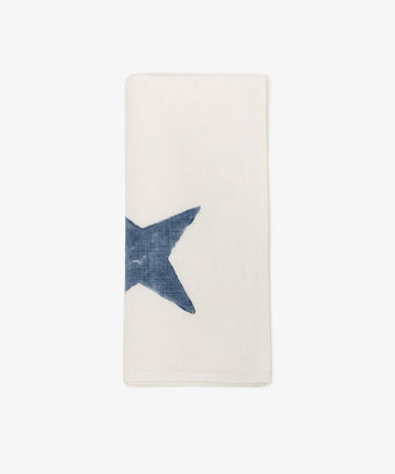 The Nova Napkin, Set of 6, features folded white cloth napkins with a large blue star partially visible on the left—ideal for elegant table settings.