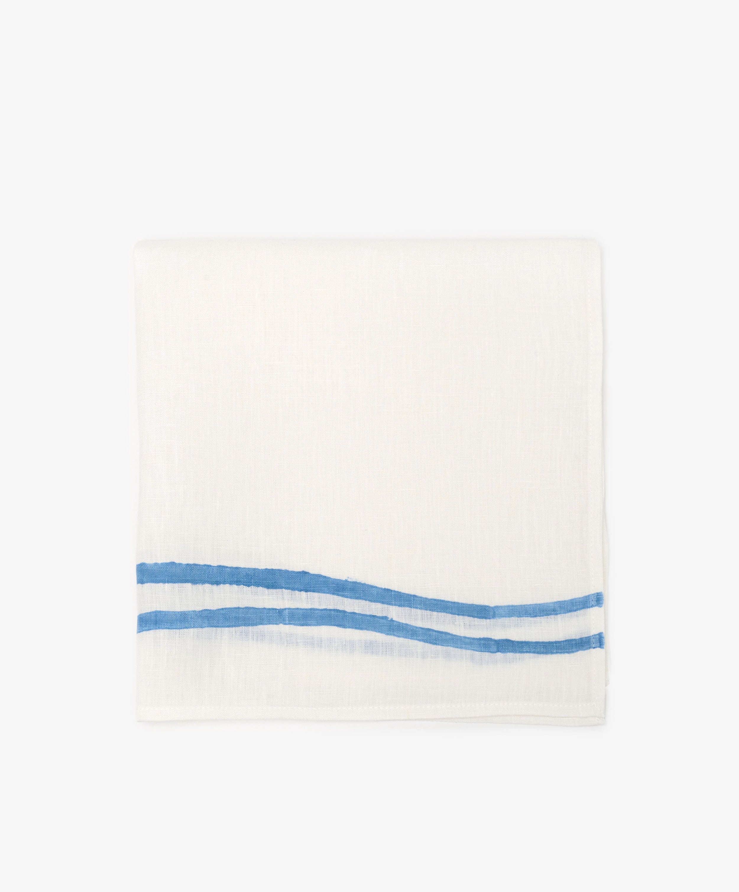 A set of 6 Onda Napkins, each made of folded white linen and hand block-printed with two parallel blue wave-like stripes along one edge, displayed against a plain background.