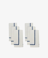Six neatly folded Riga Napkins, Set of 6, in white with a simple dark blue border, arranged in two groups on a plain white background.