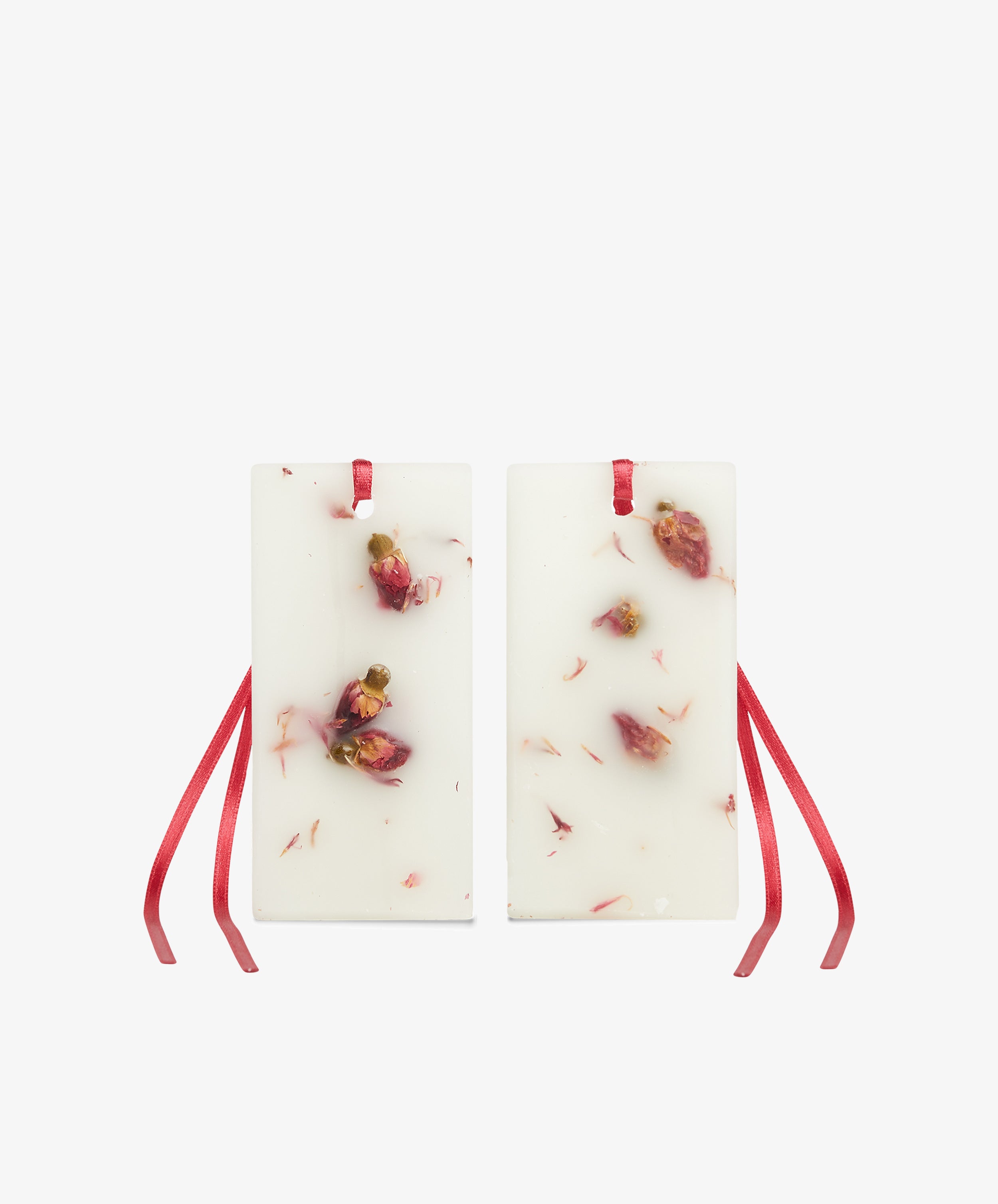 The Rosa Novella Scented Wax Tablets, Set of 2, are rectangular white wax tablets with embedded dried rose petals and red ribbon loops at the top.
