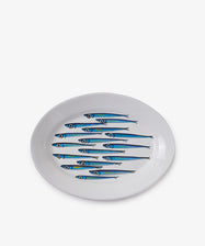 The Tommaso Oval Platter is a white ceramic plate featuring a blue and green sardine design, inspired by the vibrant sea life of the Amalfi Coast.