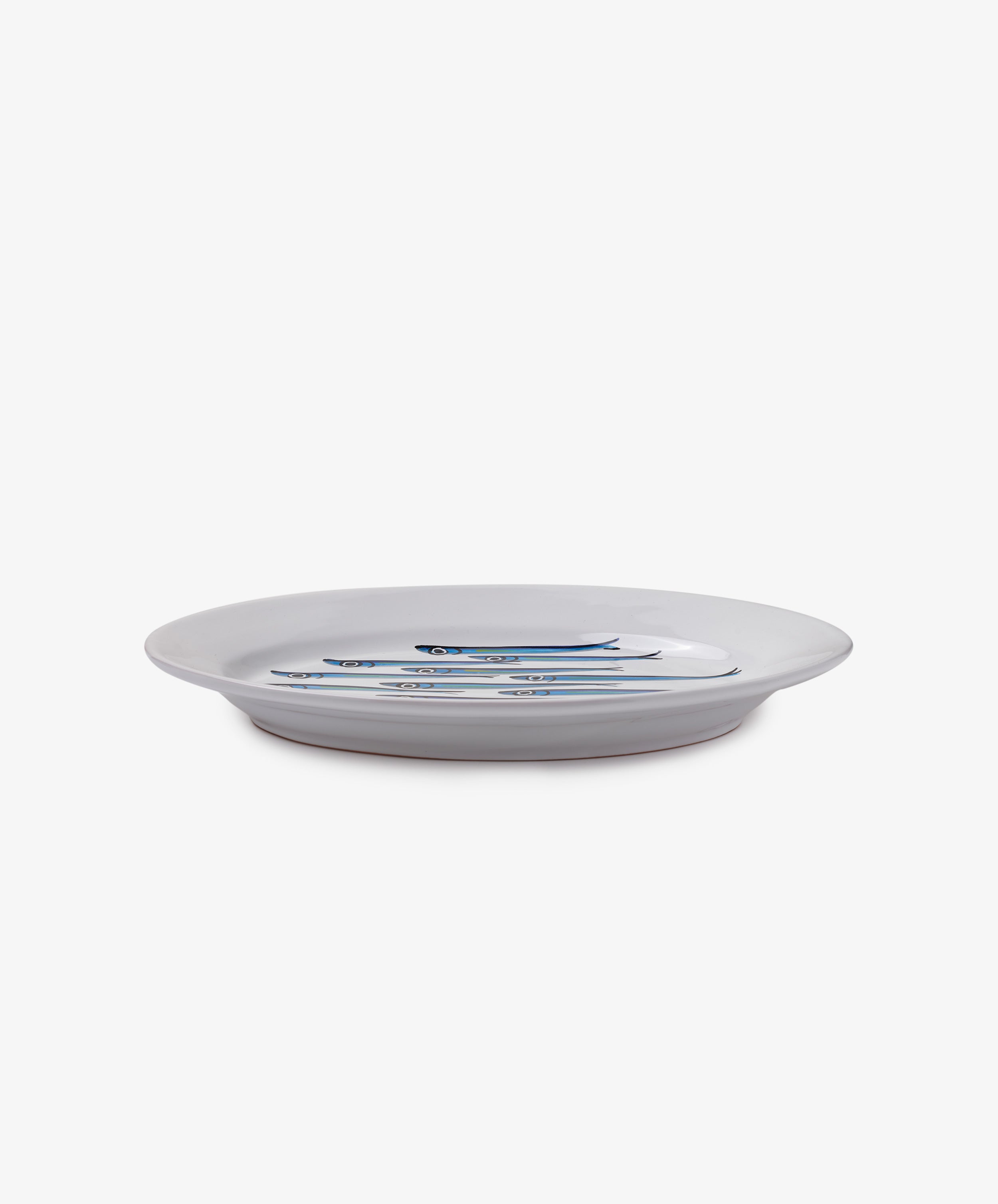 The Tommaso Oval Platter is a white ceramic plate featuring three blue and silver sardines at the center, inspired by the Amalfi Coast, set against a plain white background.