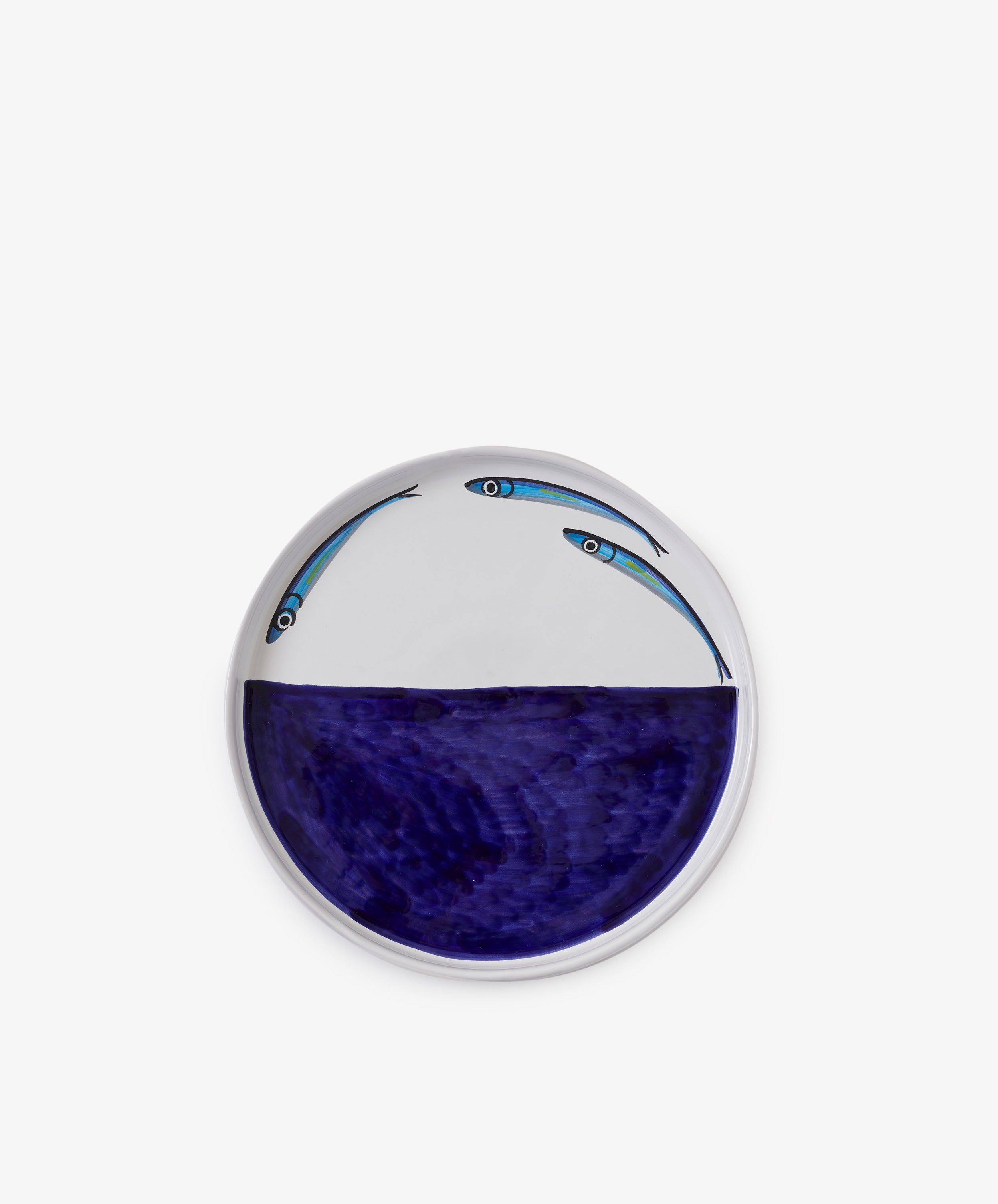 The Tommaso Flying Fish Platter is a round ceramic serving piece with a deep blue section inspired by Amalfi Coast waters and two illustrated flying fish above the blue area on a white background.