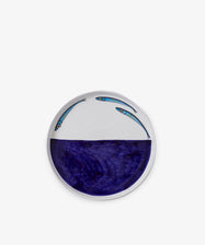 The Tommaso Flying Fish Platter is a round ceramic serving piece with a deep blue section inspired by Amalfi Coast waters and two illustrated flying fish above the blue area on a white background.