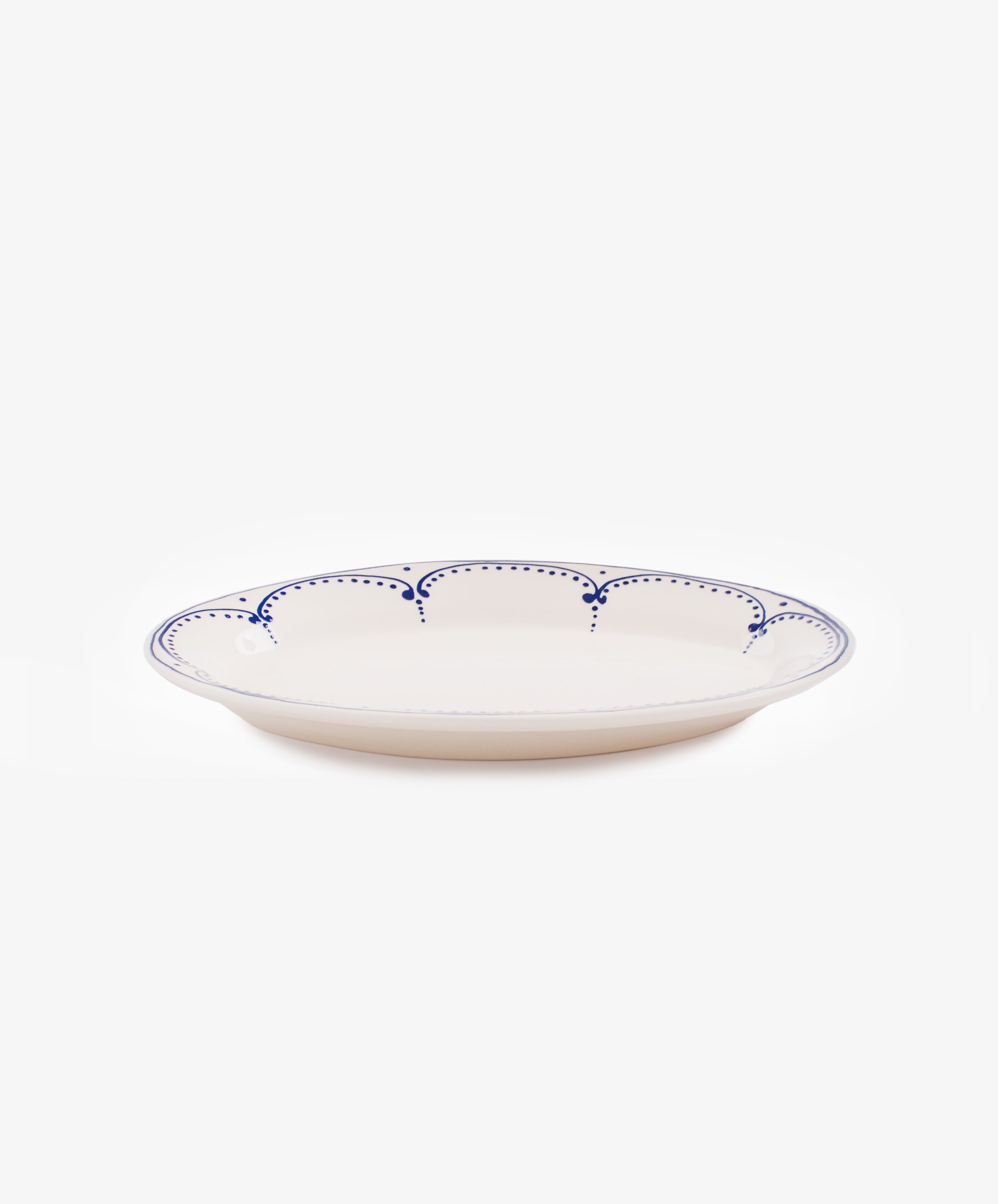 Side view of large Arco oval serving platter in white glazed ceramic with handpainted blue border design.