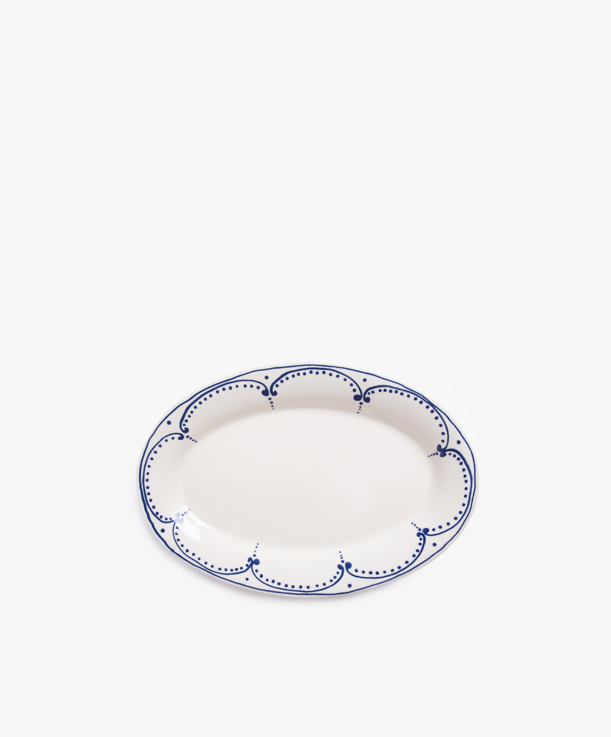 The Arco Oval Serving Platter is a white ceramic platter featuring a blue scalloped and dotted border, inspired by traditional Portuguese design, displayed on a plain white background.