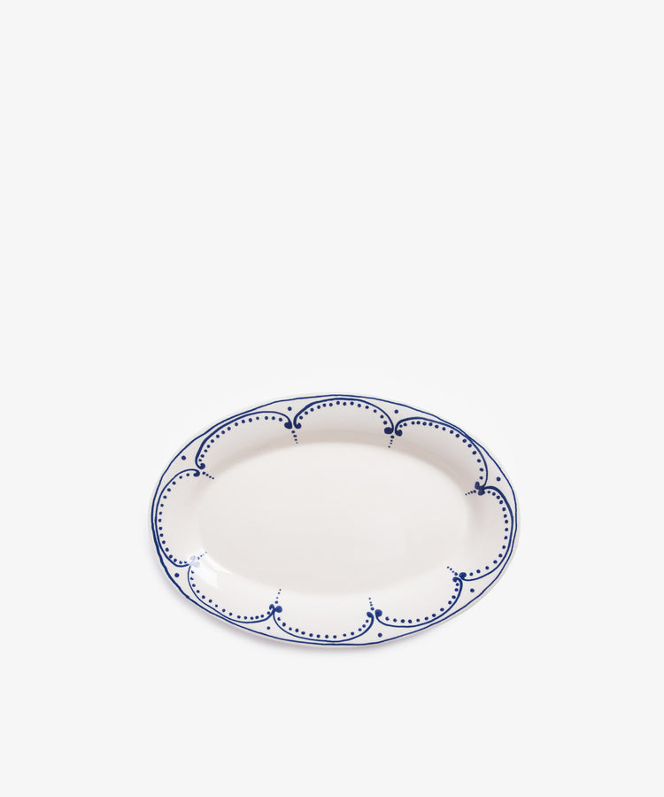 The Arco Oval Serving Platter is a white ceramic platter featuring a blue scalloped and dotted border, inspired by traditional Portuguese design, displayed on a plain white background.