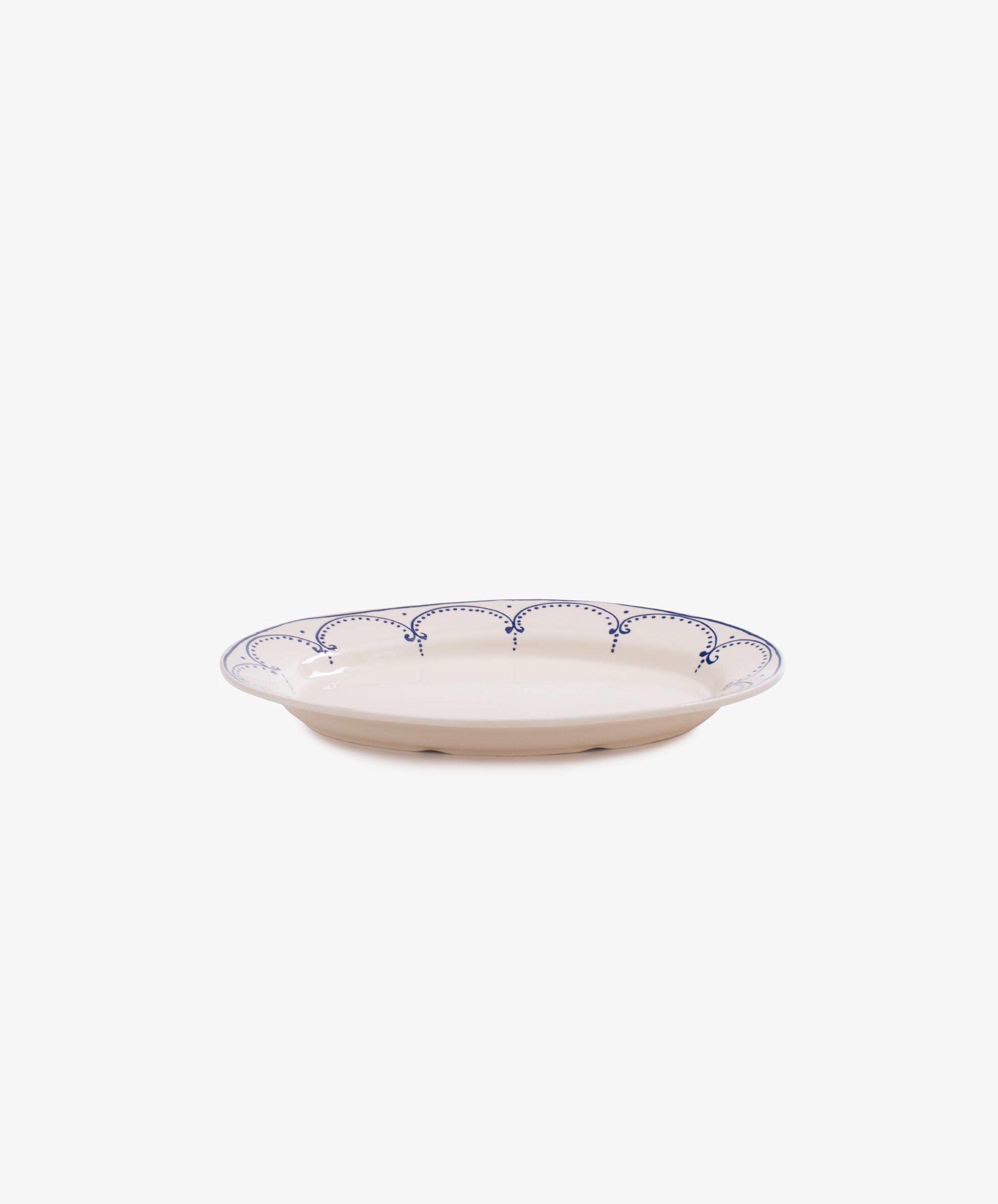 The Arco Oval Serving Platter features a shallow ceramic design with a white base and blue scalloped rim, inspired by traditional Portuguese patterns, shown against a plain white background.