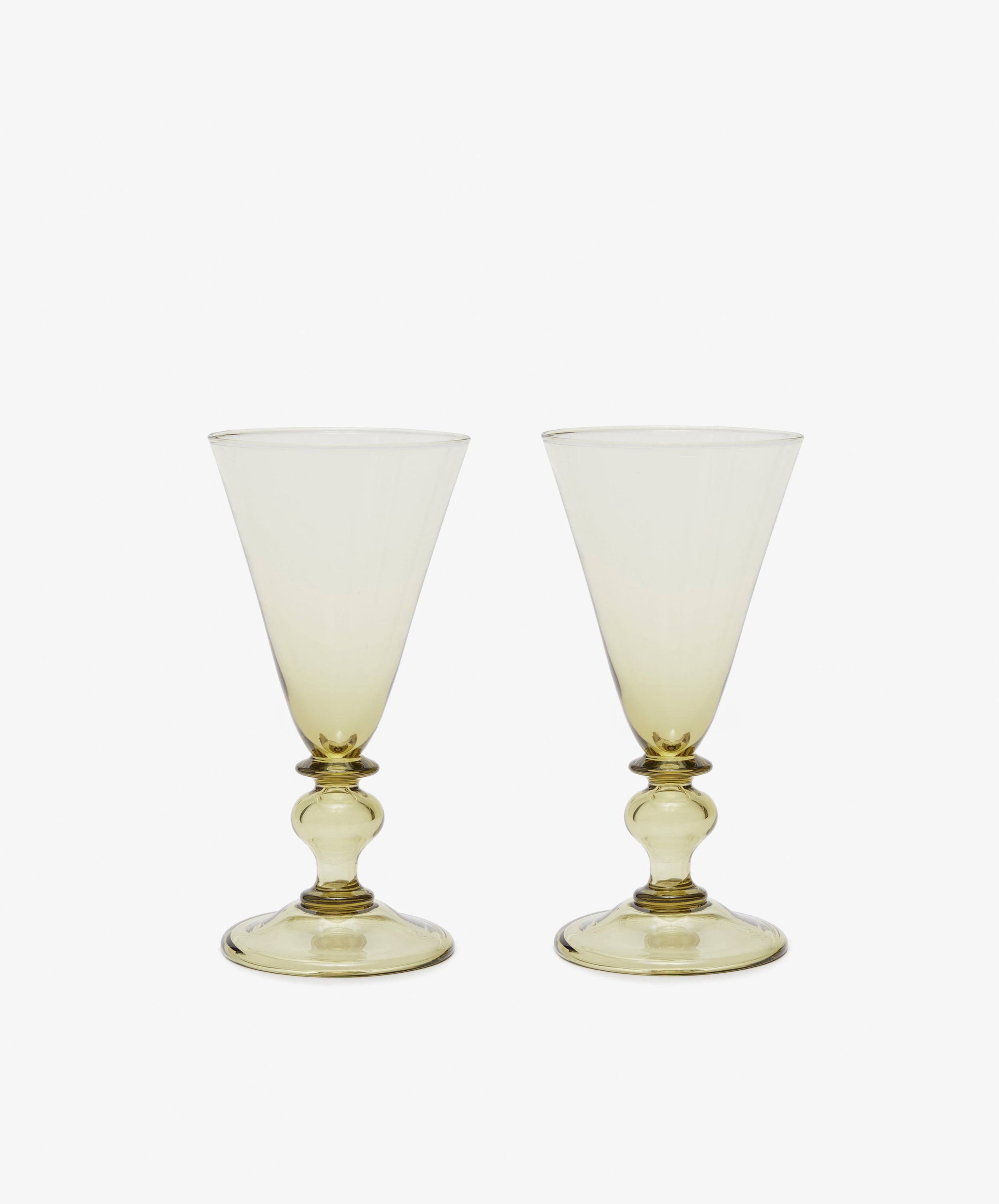 The Beata Stemmed Wine Glass set of 6 features clear, subtly yellow-tinted glasses with wide bowls and decorative stems, exuding soft elegance on a plain white background.