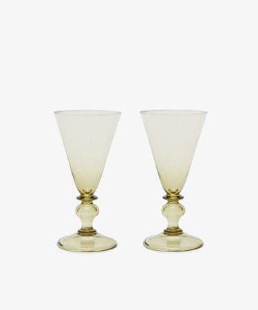 The Beata Stemmed Wine Glass set of 6 features clear, subtly yellow-tinted glasses with wide bowls and decorative stems, exuding soft elegance on a plain white background.