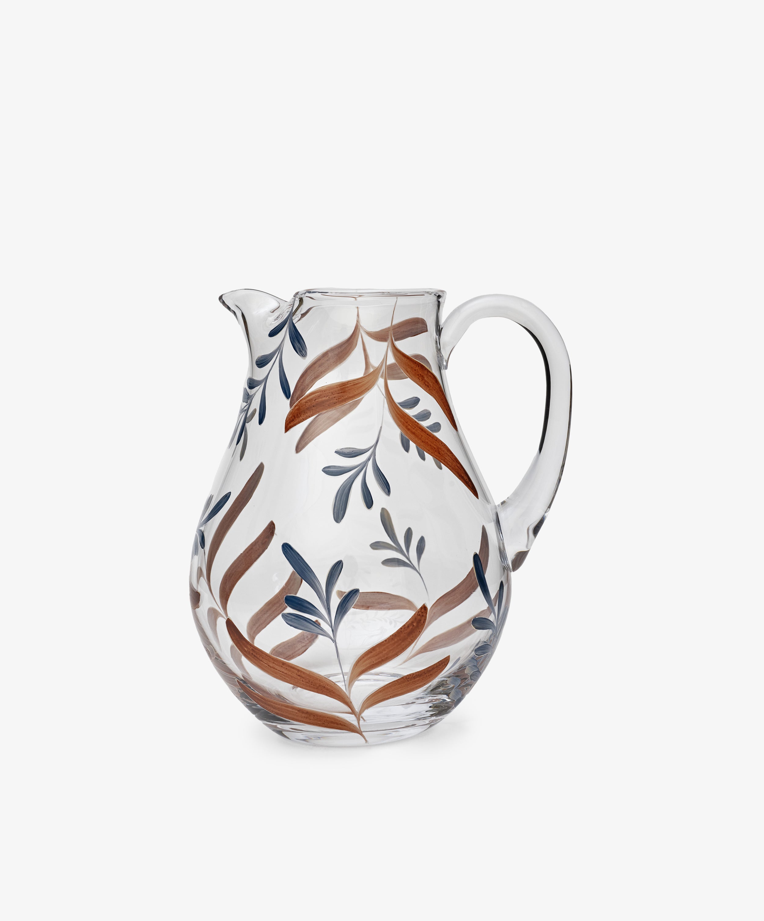 The Botanical Jug is a clear glass pitcher with a handle, featuring brown and blue leafy designs. This handmade jug adds a unique touch to your tableware and is photographed against a plain white background.