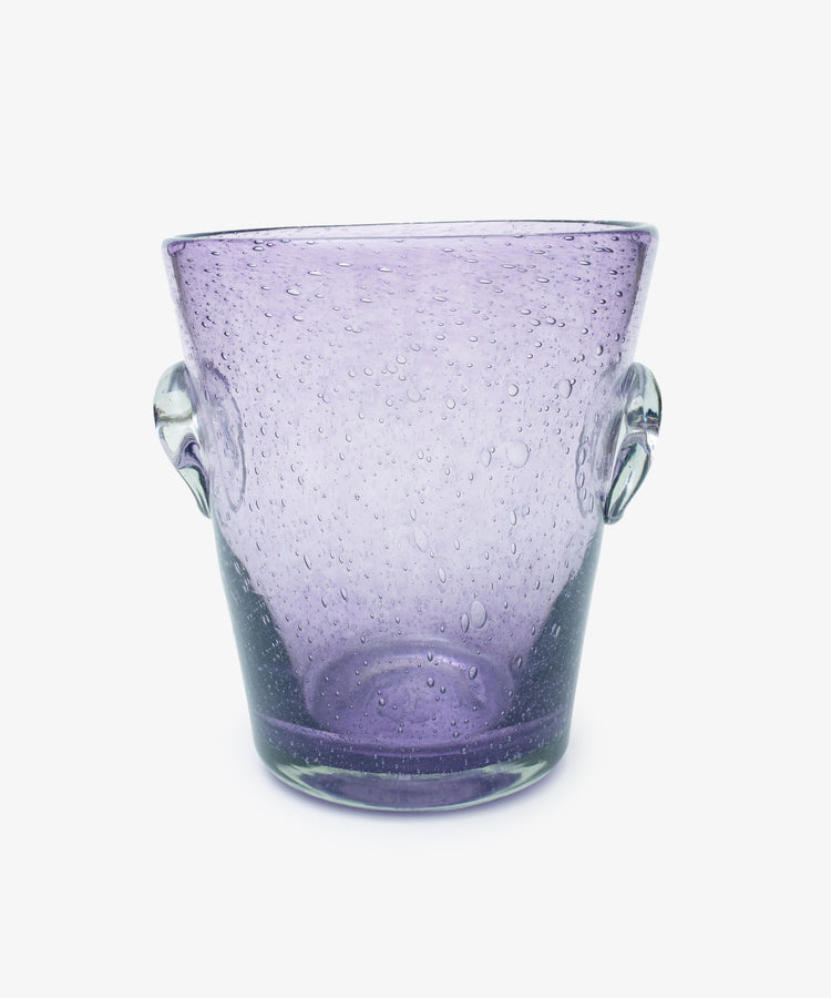 The Lauren Champagne Bucket is a translucent purple glass ice bucket with two clear side handles and air bubbles throughout, set against a white background.