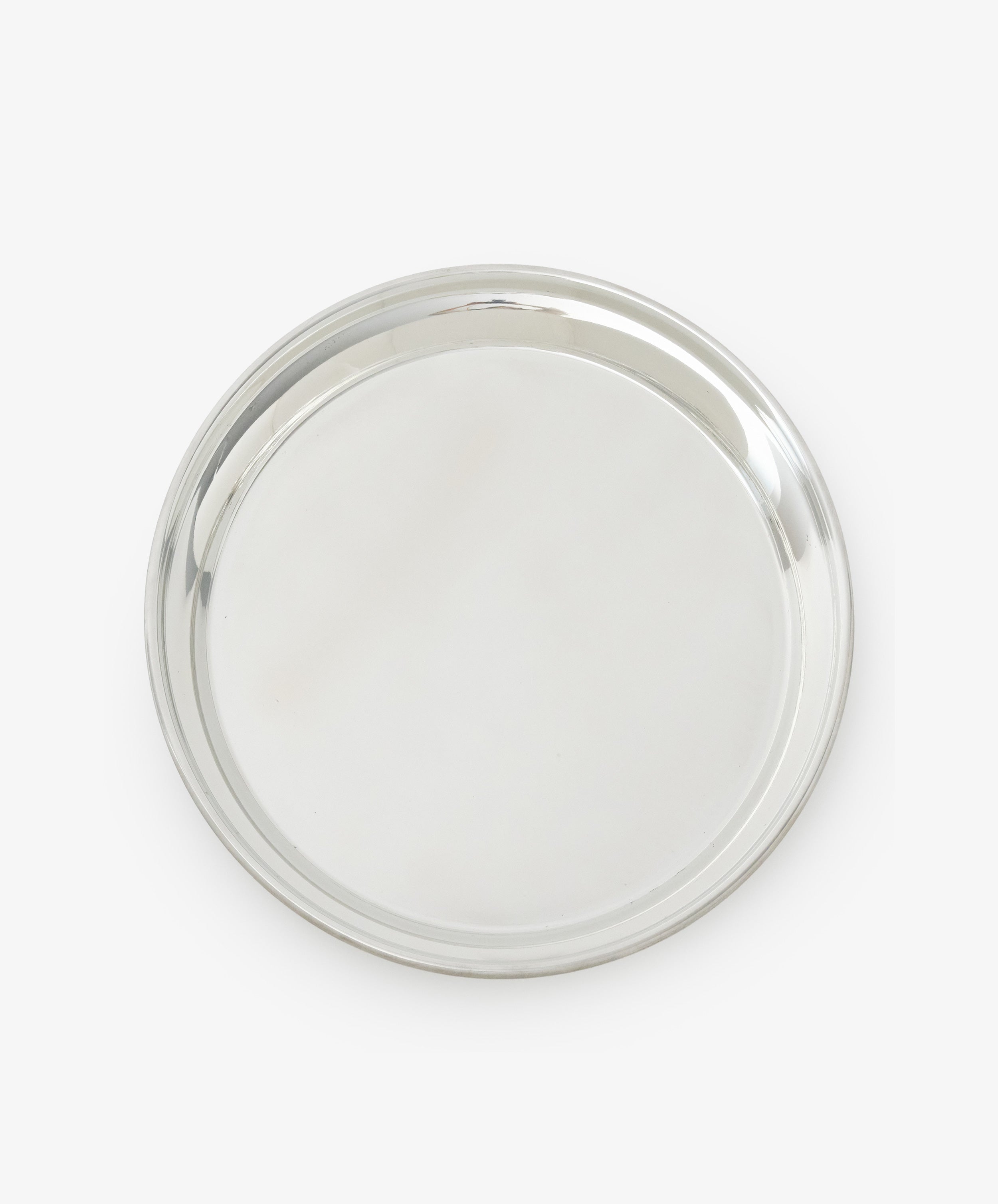 The Sophie Tray is a round, silver-toned piece with a raised edge, crafted from tarnish-free pewter and showcasing a minimalist design against a white background.