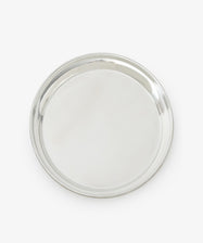 The Sophie Tray is a round, silver-toned piece with a raised edge, crafted from tarnish-free pewter and showcasing a minimalist design against a white background.