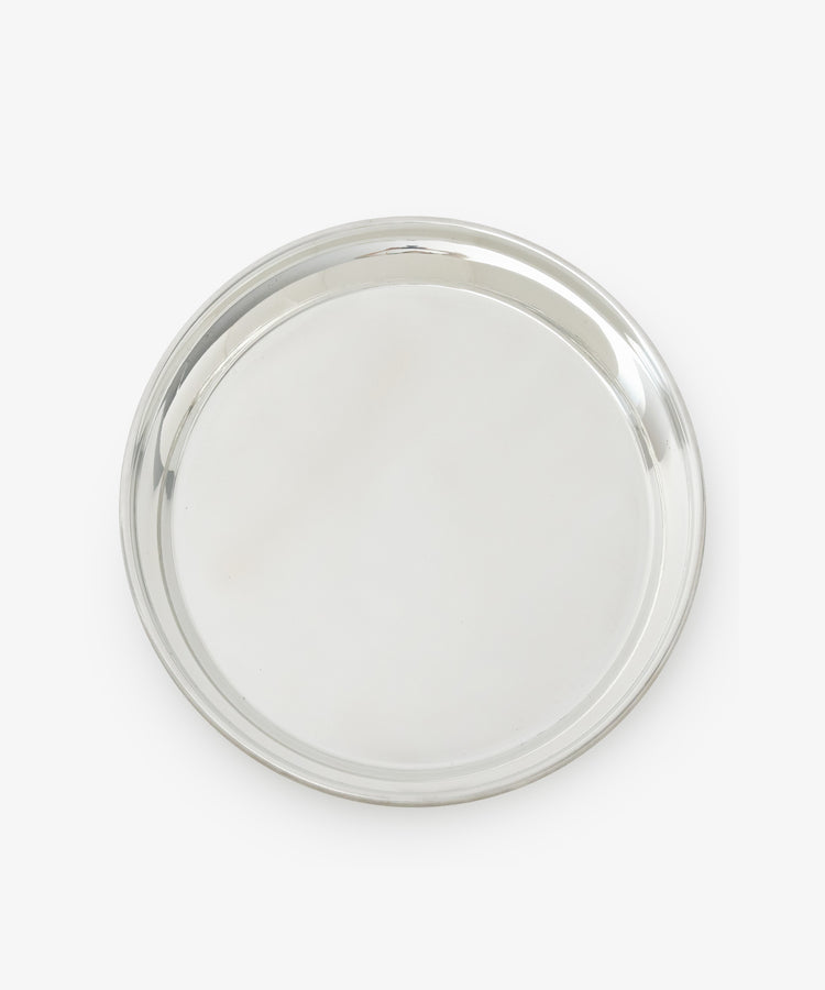 The Sophie Tray is a round, silver-toned piece with a raised edge, crafted from tarnish-free pewter and showcasing a minimalist design against a white background.