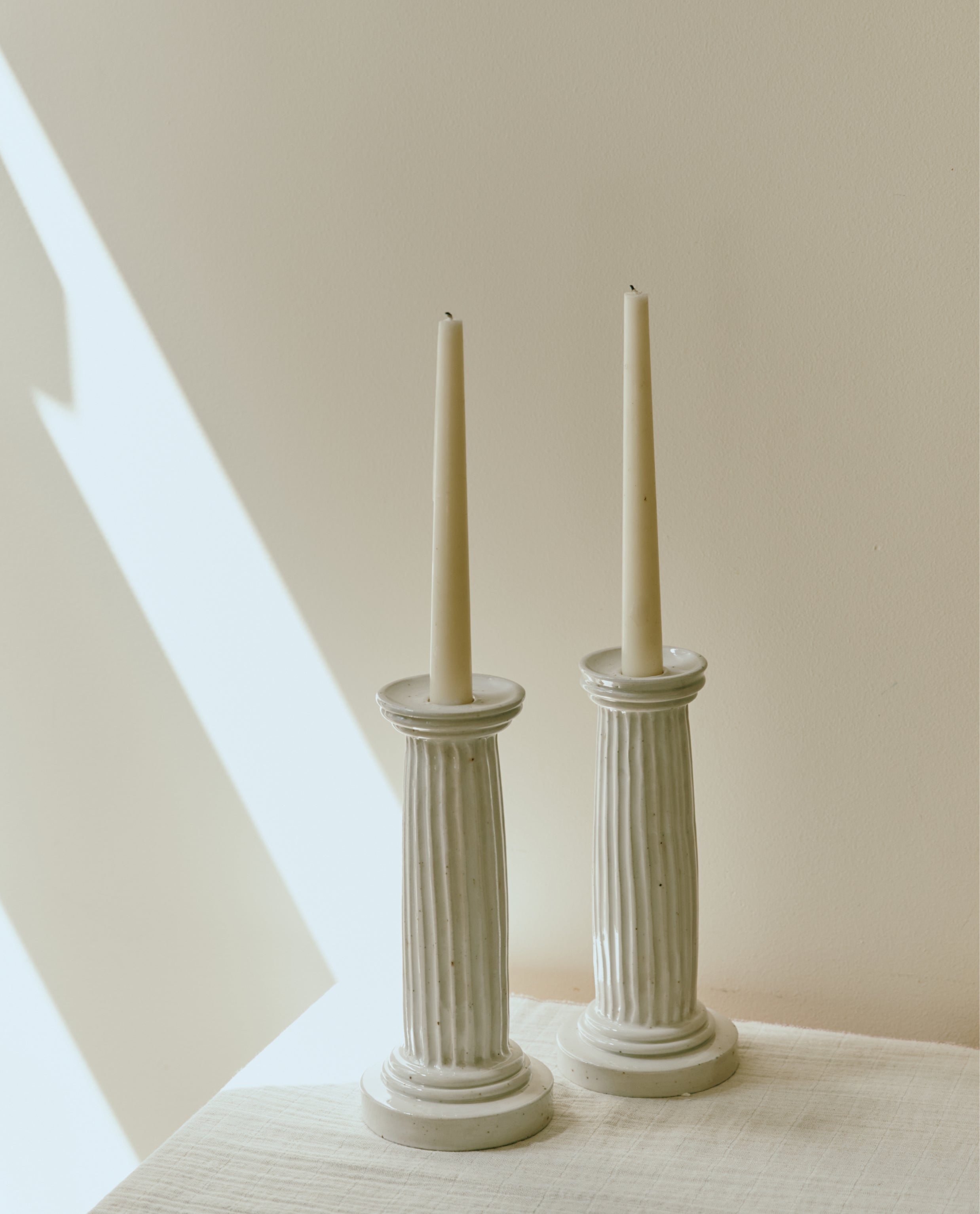 A Gift Card lets you shop beautiful items like two tall, unlit white taper candles in fluted ceramic holders—perfect for gifting or redeeming at checkout.