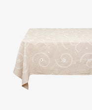 Tan cotton Inez Tablecloth with white embroidery spread and draped over invisible table.