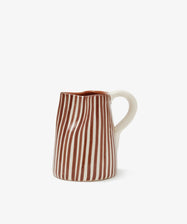 The Natalia Milk Jug features vertical brown and white stripes with a white handle, handmade to add charm to your breakfast table, shown against a plain white background.