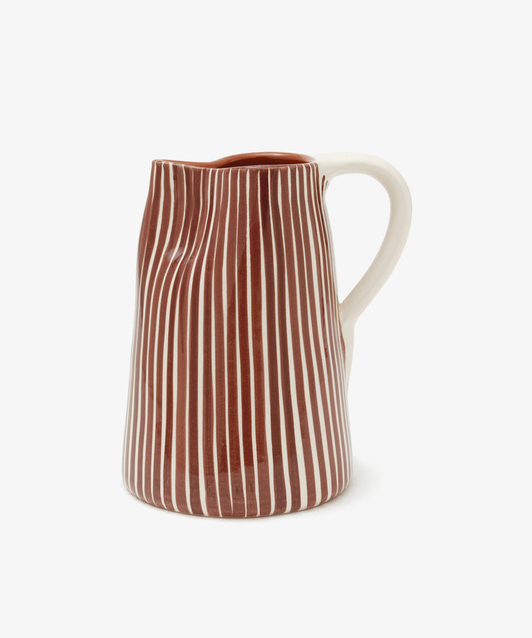 The Natalia Water Jug is a ceramic jug with a white handle and body, featuring vertical brown and white stripes. It is photographed against a plain white background.