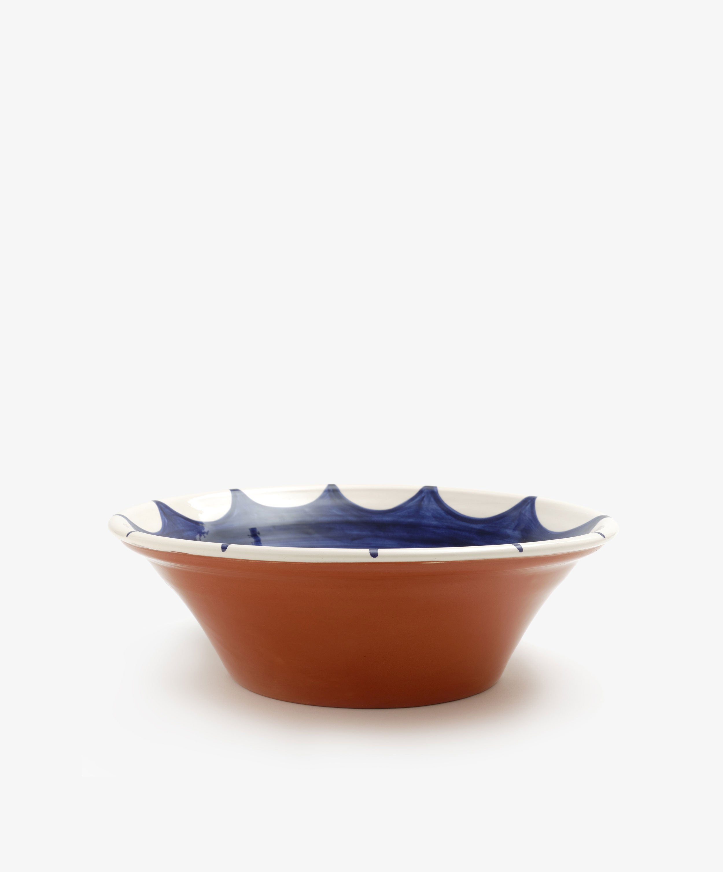 Stella Serving Bowl. Glazed terracotta bowl with white rim and dark blue design, side view.