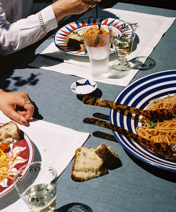 Natalia Platter in situ on tablecloth, holding pasta with diners' hands in view.