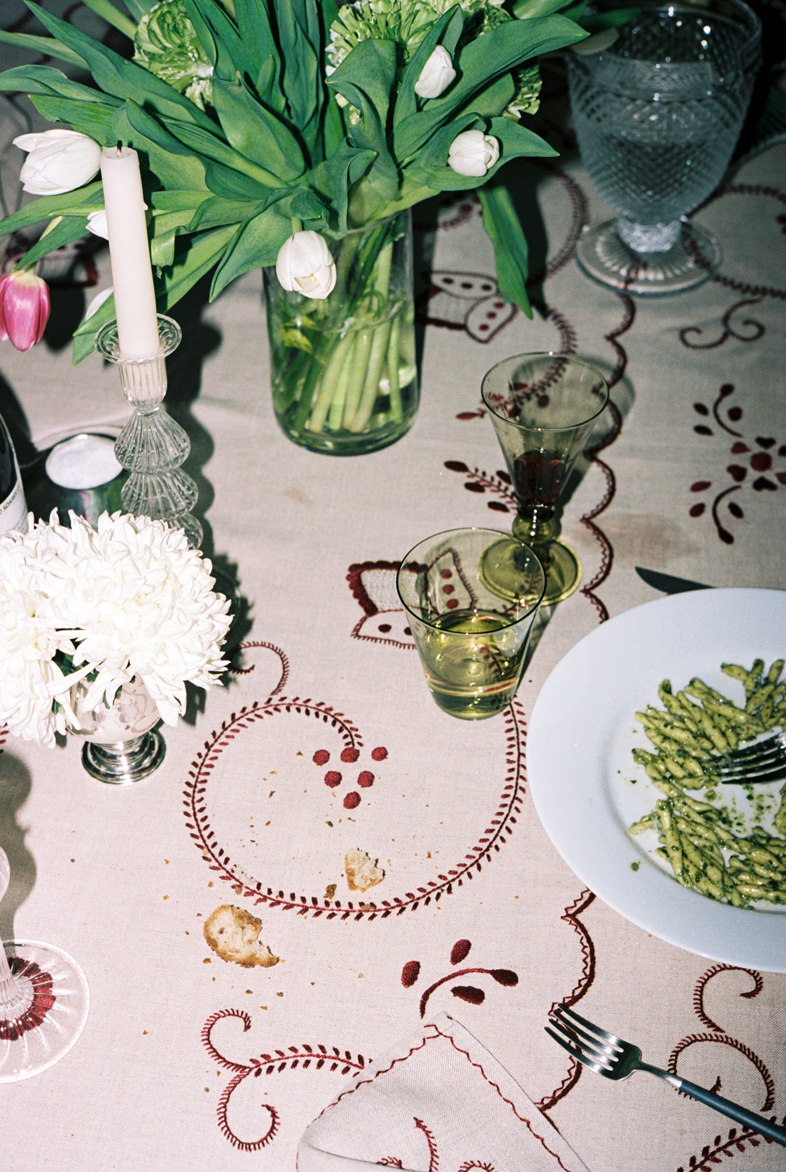 Dinner party image of Inez Tablecloth covered in food, flowers and glasses.