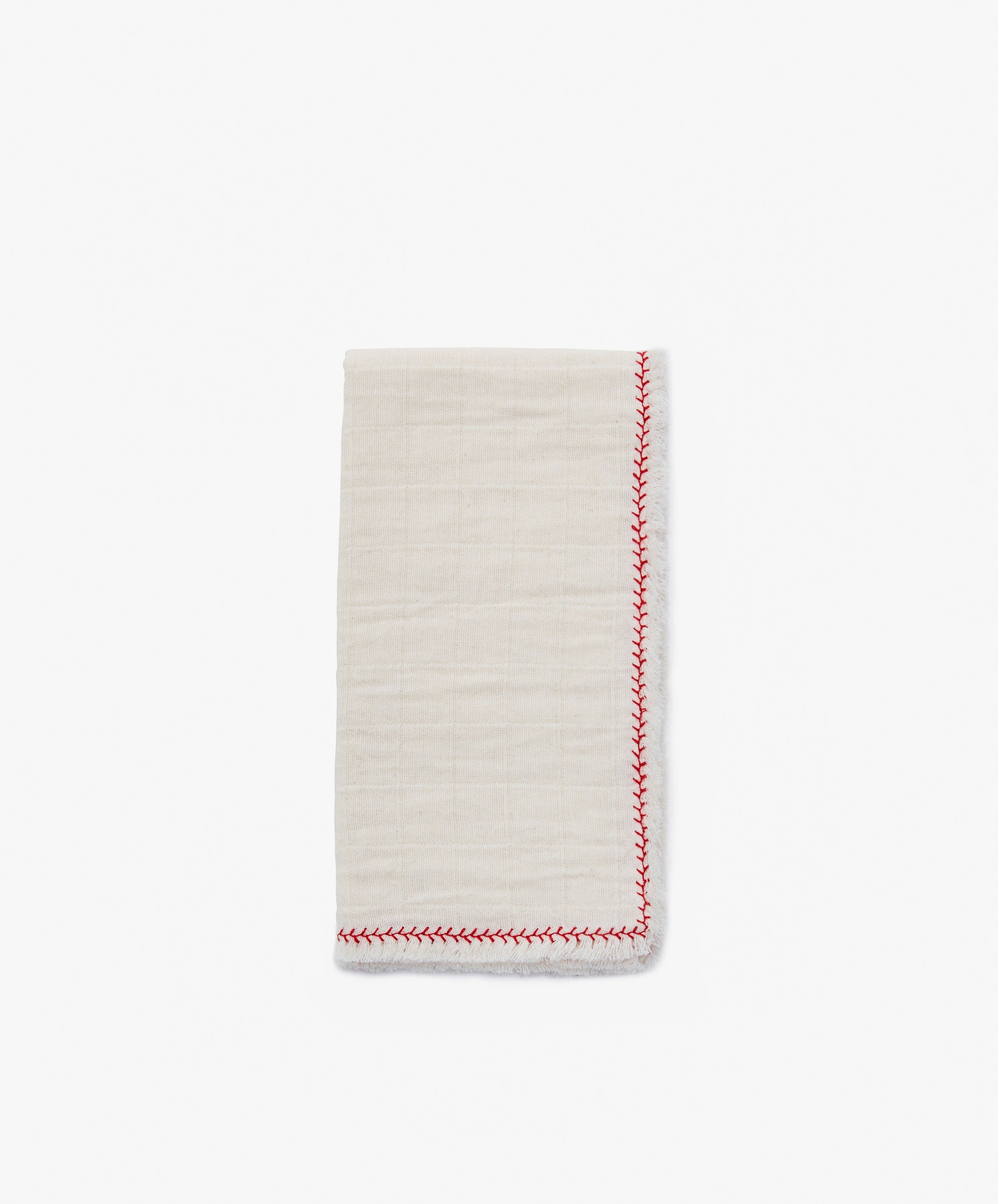 A folded Filial Napkin, Set of 6, in off-white cotton with a red decorative edge stitch, rests on a plain white tabletop.