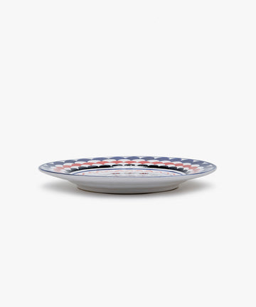 Palio Dinner Plate. Glazed ceramic in red and navy designs with porcupine motif, angled side view.