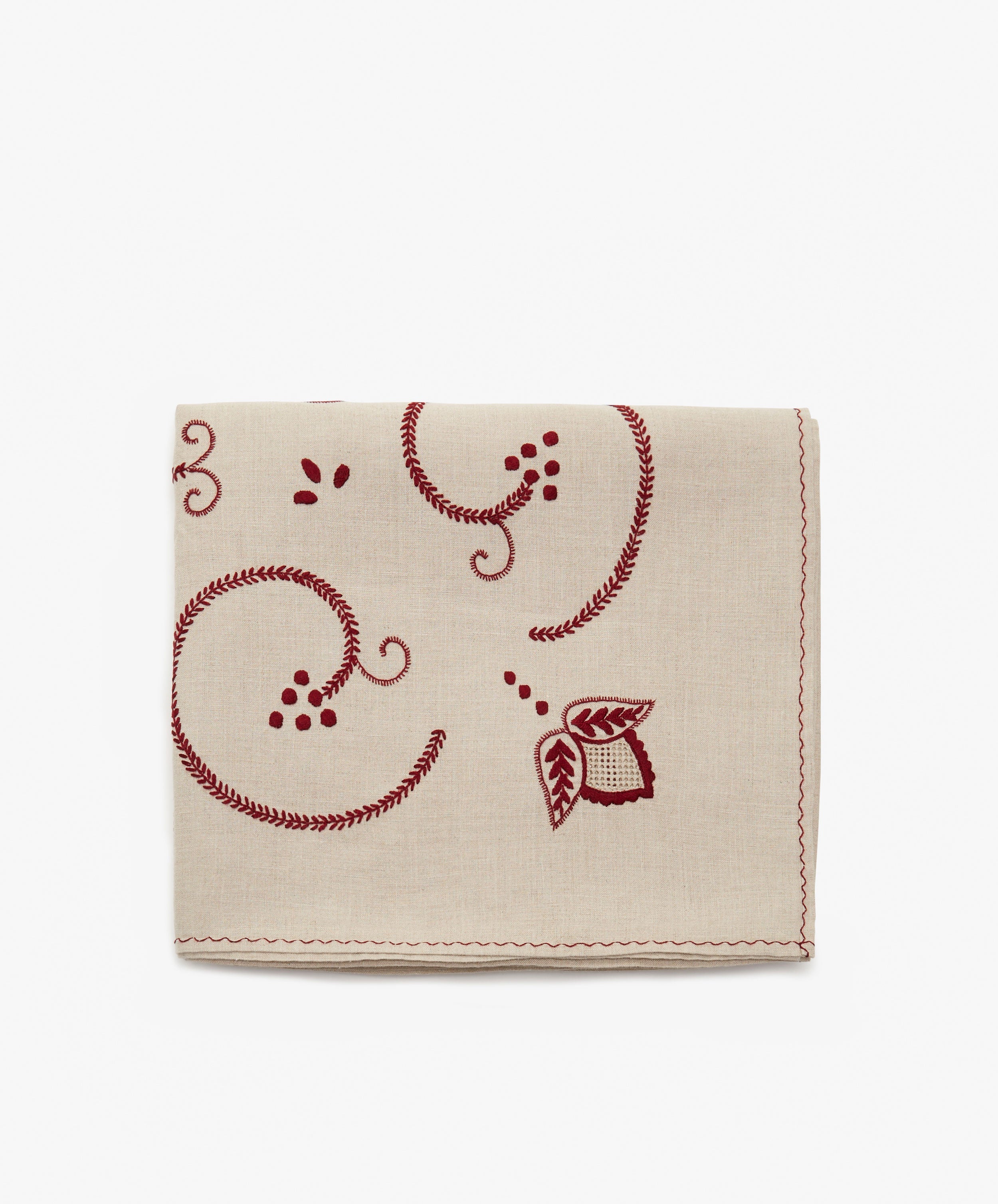 Inez Tablecloth. Folded cloth in tan cotton with red embroidered floral motif.