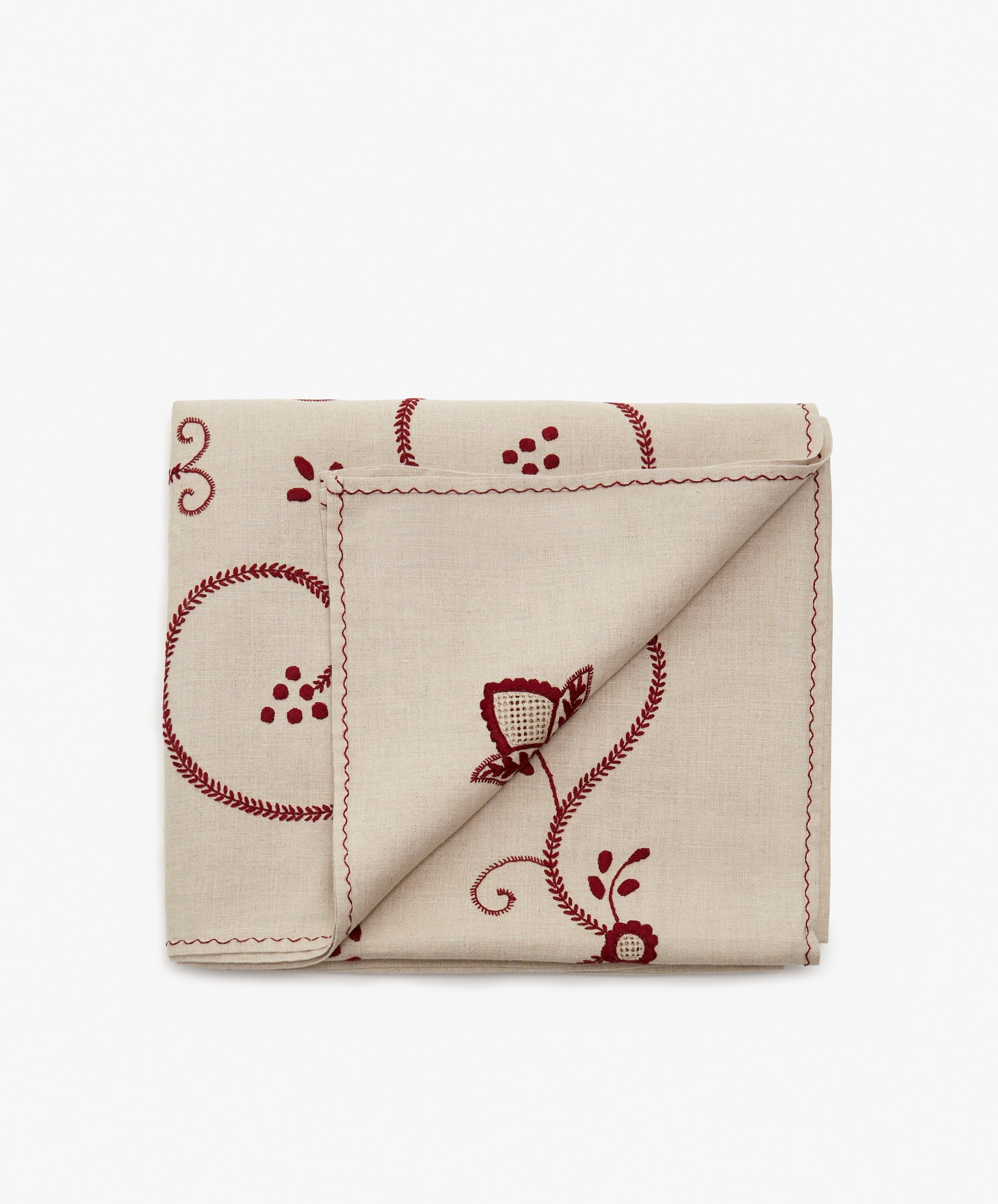 Inez Tablecloth in tan cotton and red embroidery, folded with corner flipped up.