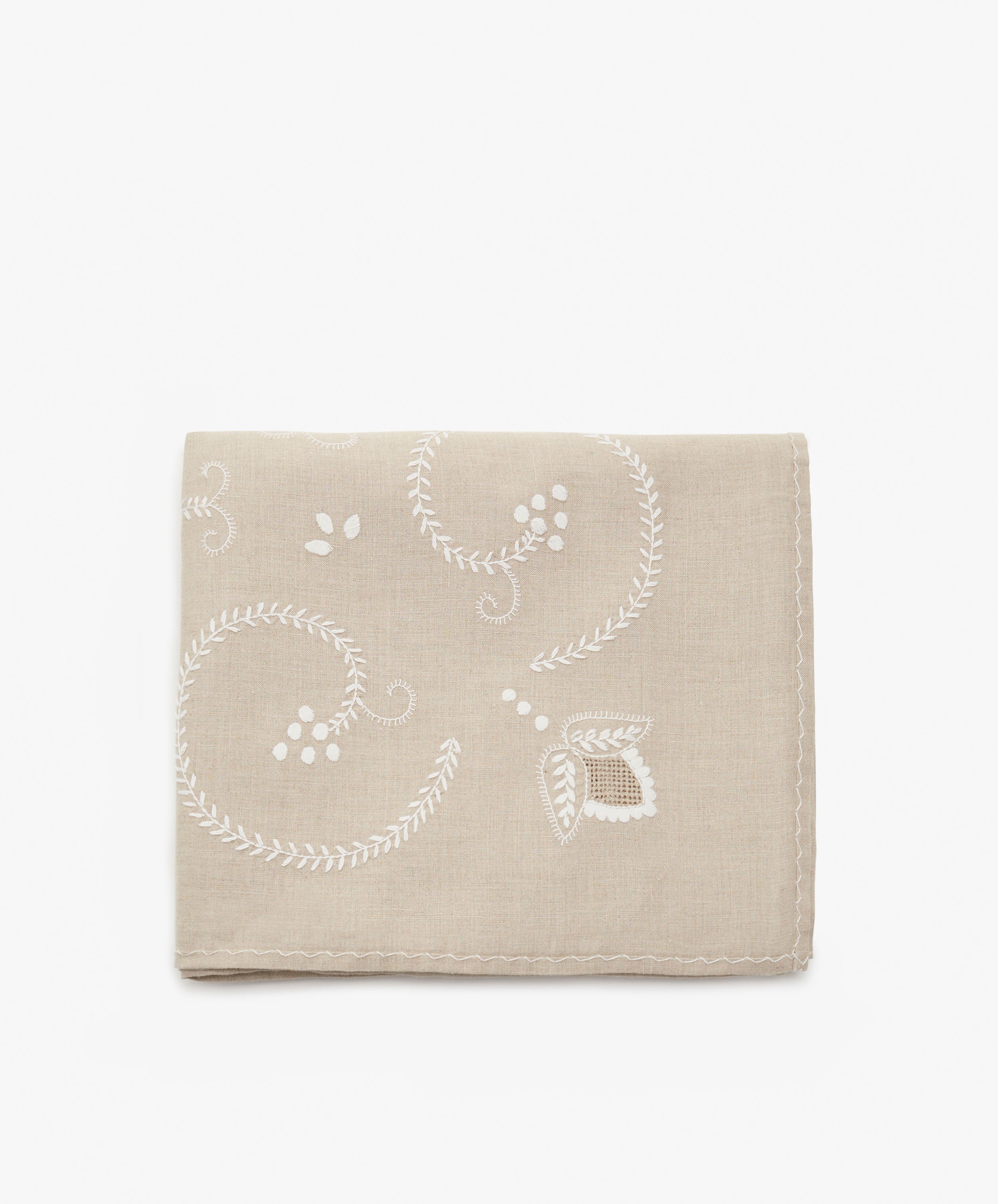 Inez Tablecloth. Folded cloth in tan cotton with white embroidered floral motif.