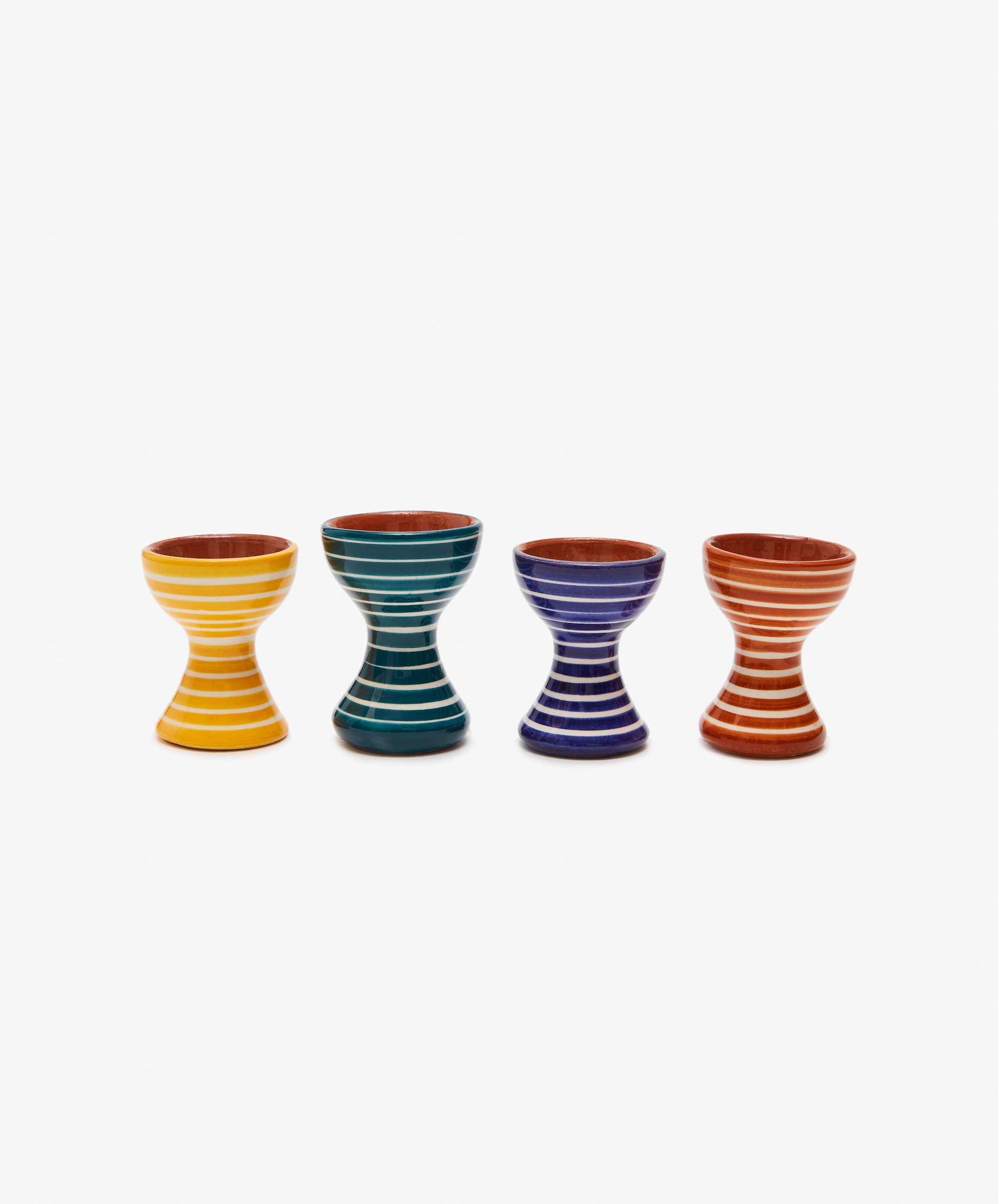 Line up of four striped egg cups in yellow, green, blue, and orange.