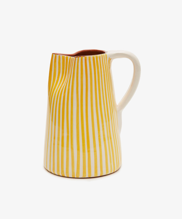 The Natalia Water Jug is a handmade ceramic piece featuring an uneven, crumpled shape, a white handle, and vertical yellow stripes.