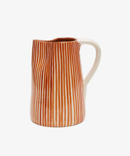The Natalia Water Jug features vertical orange and white stripes with a white handle, displayed against a plain white background.