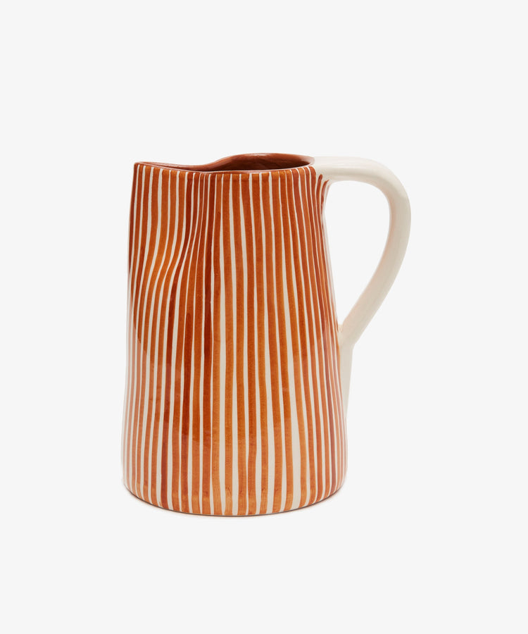 The Natalia Water Jug features vertical orange and white stripes with a white handle, displayed against a plain white background.