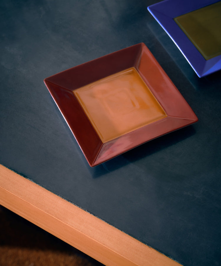 red and orange square plate and blue and green square plate on black table