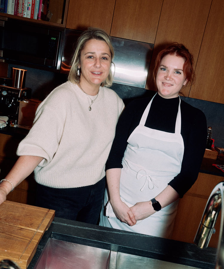 two woman at the kitchen smiling at the camera